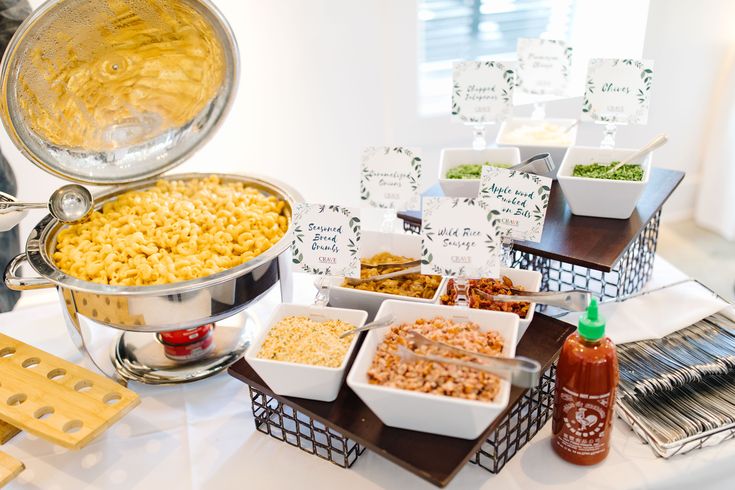 a buffet table filled with different types of food and condiments on it, including macaroni and cheese