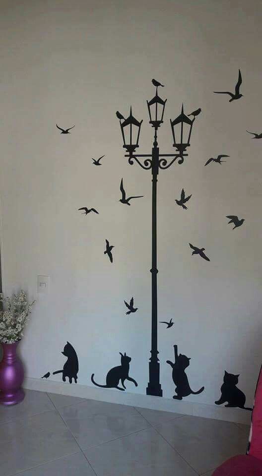 a lamp post with cats and birds on it next to a purple vase filled with flowers