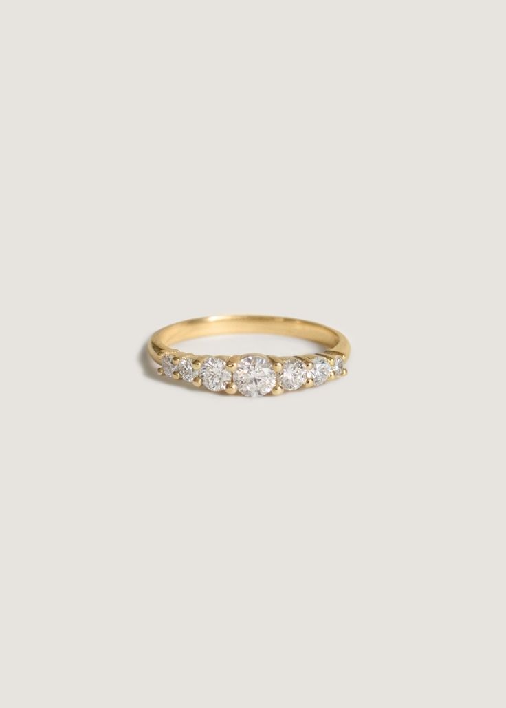 a yellow gold ring with five diamonds on the top and bottom, set against a white background