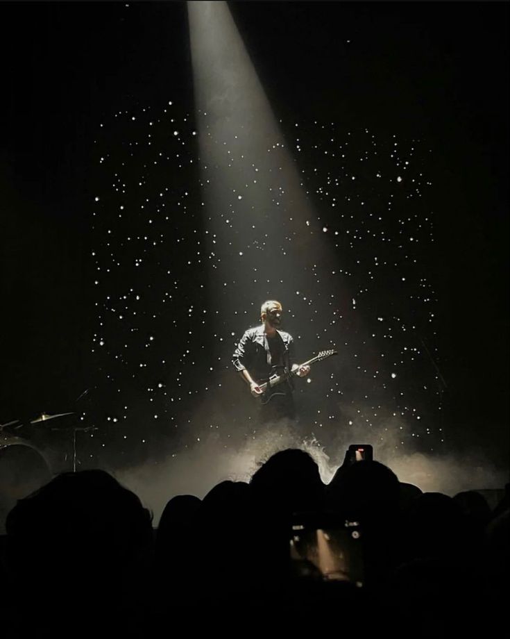 a man standing on top of a stage next to a microphone in front of a crowd