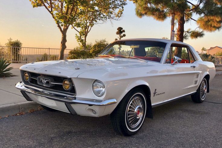 an old mustang is parked on the side of the road