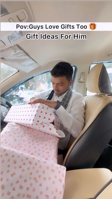 a man sitting in the back seat of a car holding two wrapped gifts