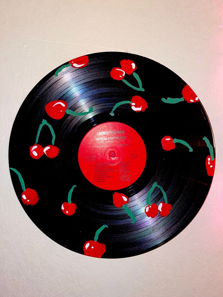 a vinyl record with cherries on it hanging from the side of a white wall