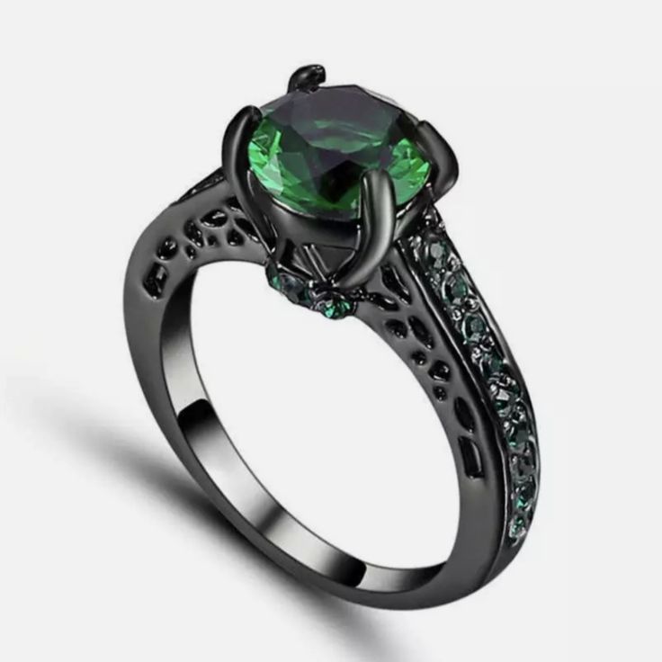 an engagement ring with green and black diamonds on the side, in front of a colorful background