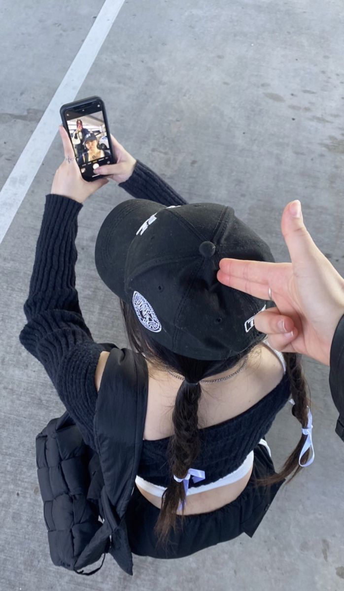 a woman holding up her cell phone to take a selfie while sitting on the ground