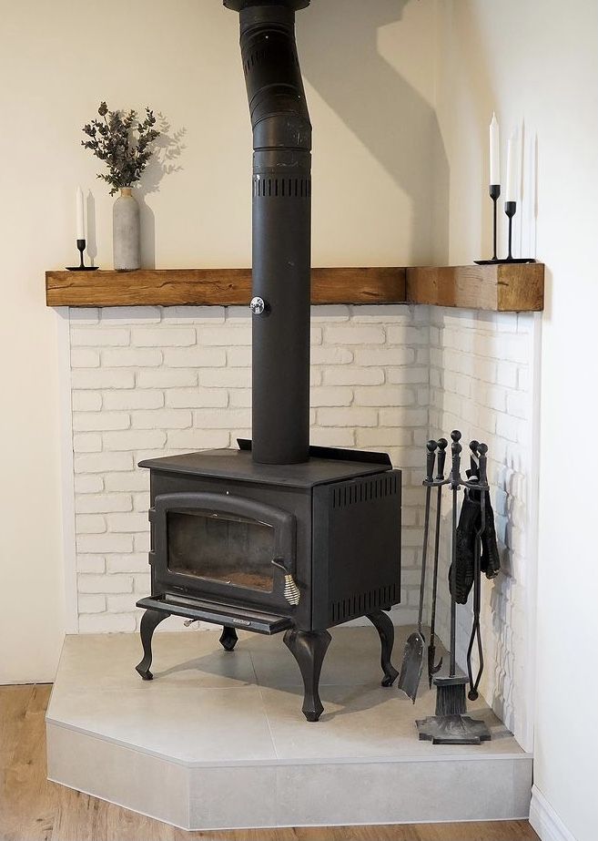 a black stove sitting on top of a wooden floor next to a white brick wall