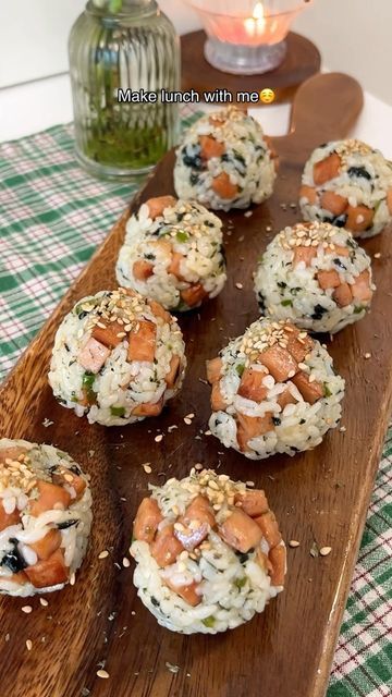 several sushi rolls on a wooden board next to a lit candle and glass vase