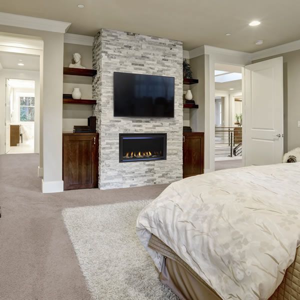 a bedroom with a bed, fireplace and entertainment center