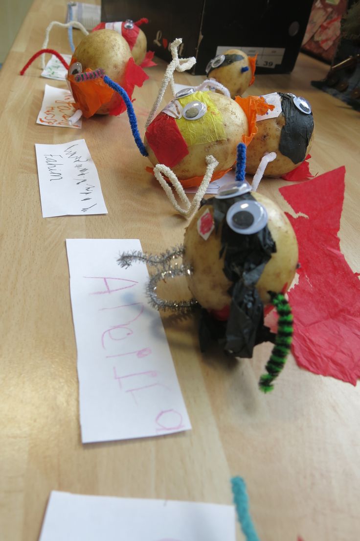 some very cute little toys sitting on a table with paper and scissors in front of them