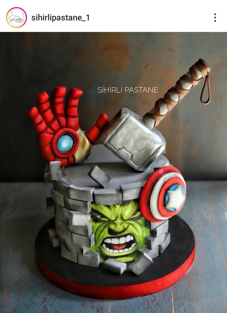 a cake made to look like the avengerss head with an iron hammer on top