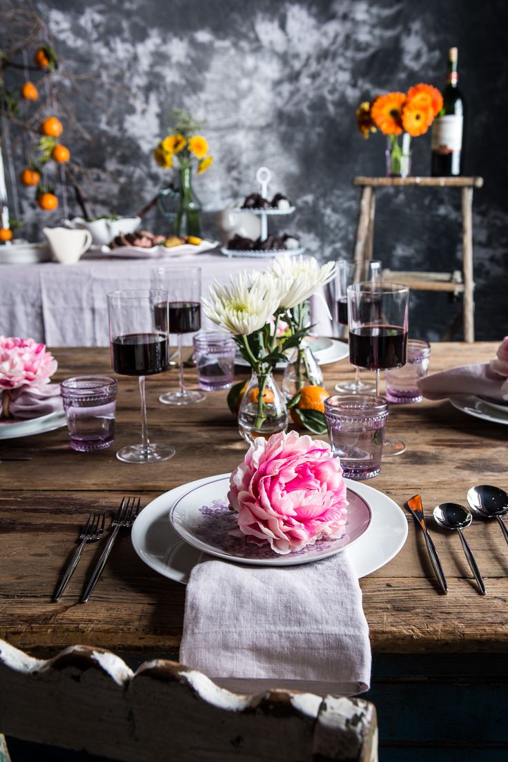 a wooden table topped with plates and glasses filled with flowers