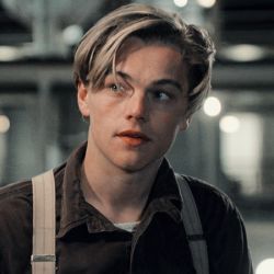 a young man with suspenders looking at the camera