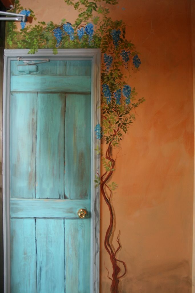 an open door with blue flowers painted on the wall next to a potted plant