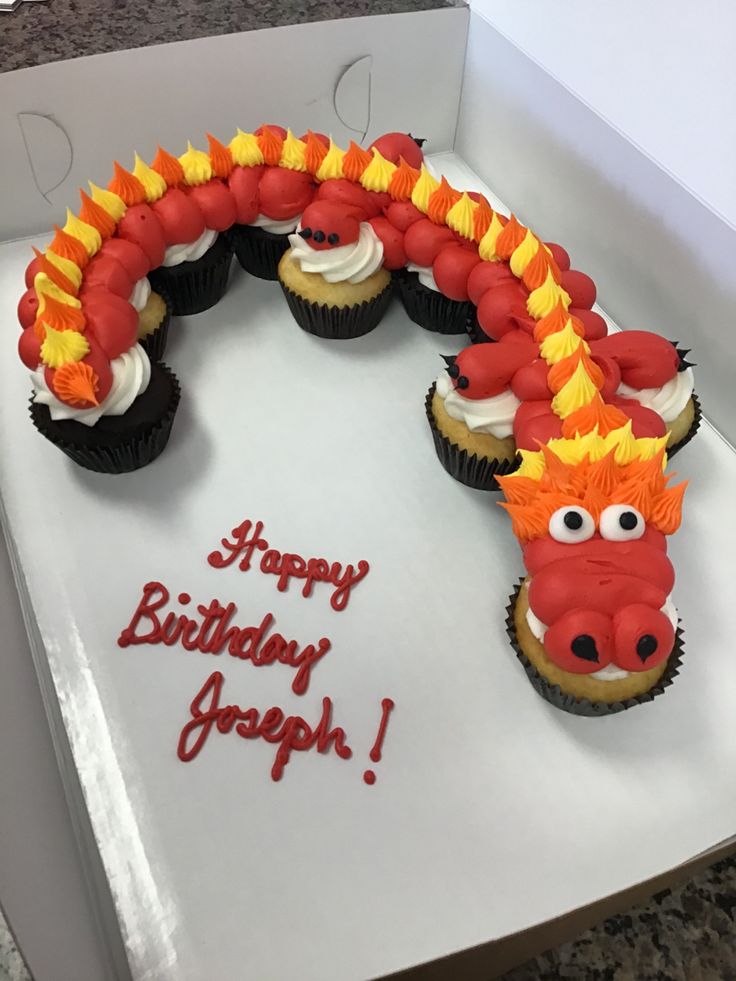 a birthday cake with cupcakes in the shape of a dragon