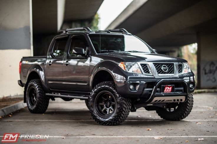 a black nissan truck parked in a parking lot next to an overpass and bridge