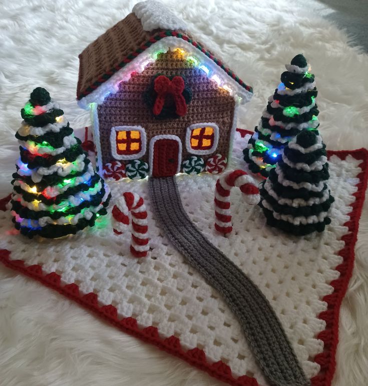 a crocheted christmas scene with a gingerbread house, trees and candy canes