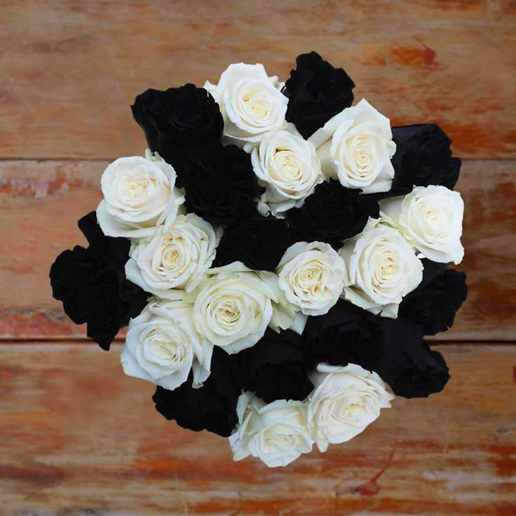 a bouquet of white and black roses on a wooden table