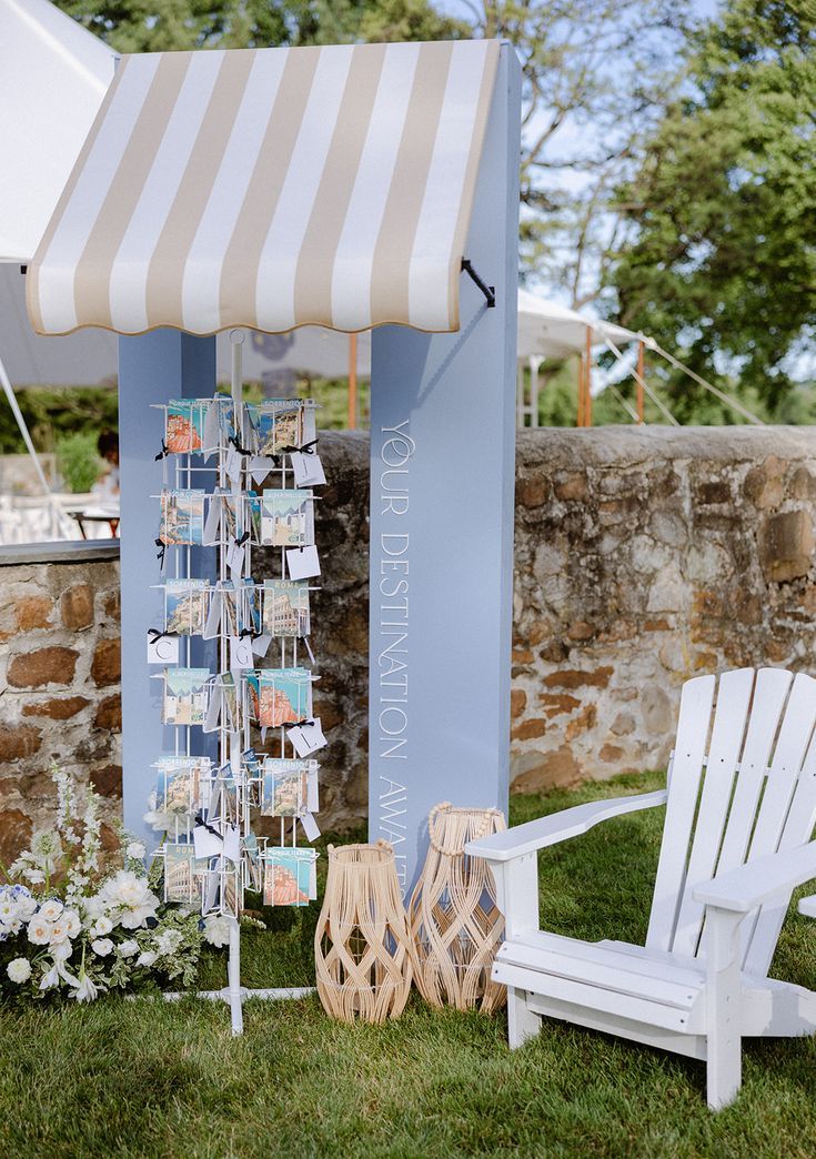 a white chair sitting in the grass next to a blue and white stand with cards on it