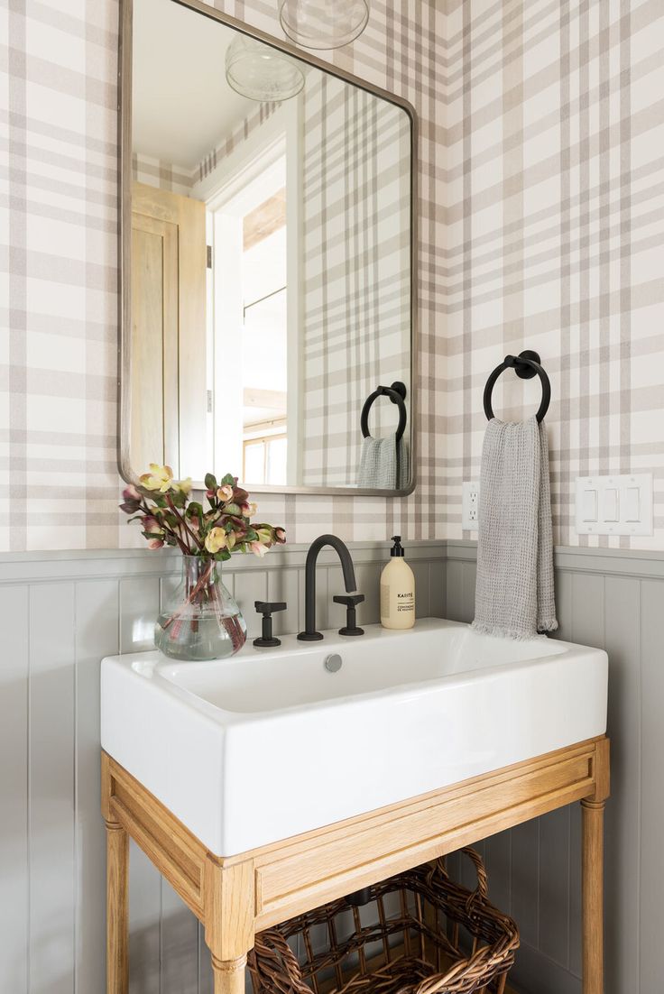 a white sink sitting under a bathroom mirror next to a wooden table with a basket underneath it