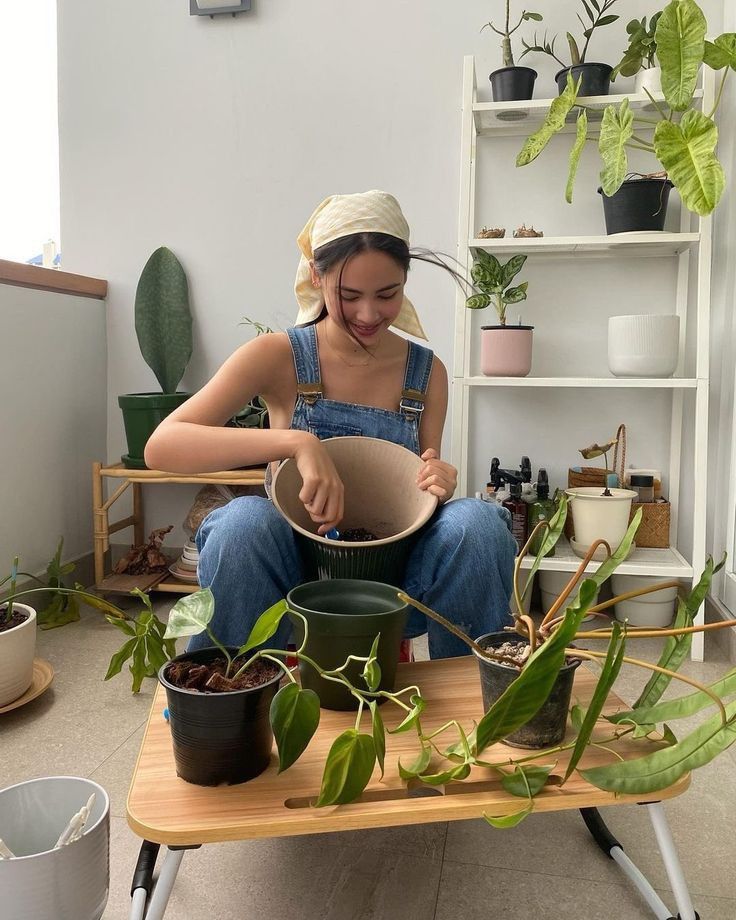 a woman sitting on a table with potted plants