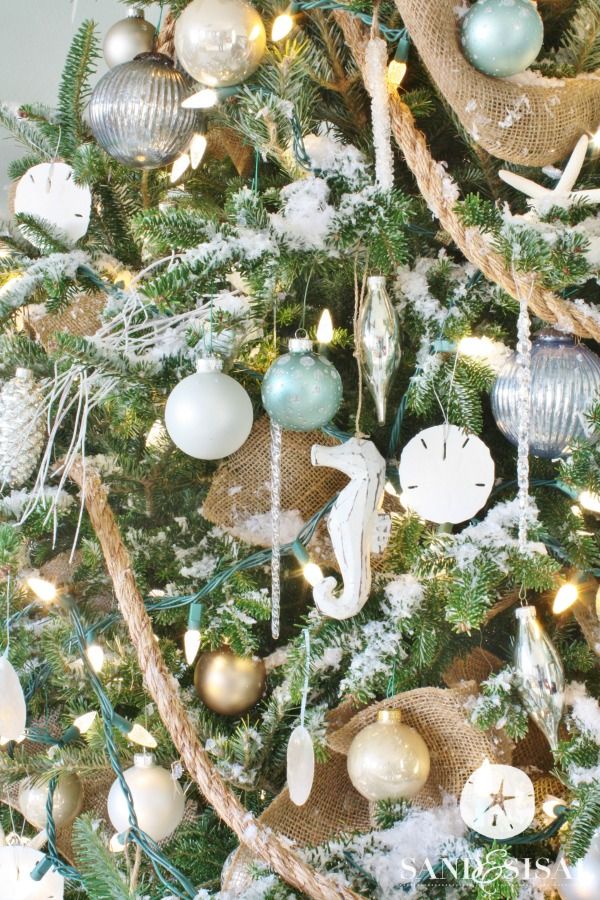 a decorated christmas tree with ornaments and lights on the branches in gold, silver and white