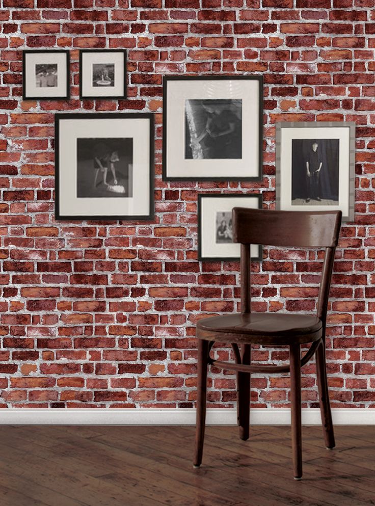 a wooden chair sitting in front of a brick wall with pictures on the wall behind it