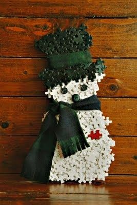 a snowman made out of buttons on a wooden wall with a green hat and scarf