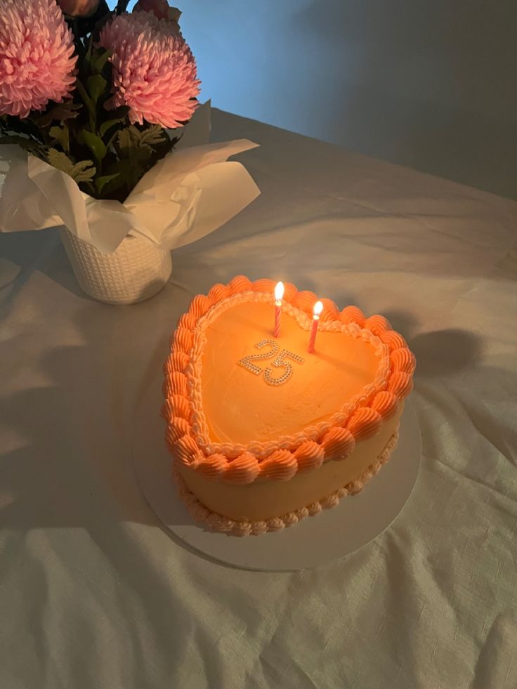 a heart shaped cake sitting on top of a table next to a vase with flowers