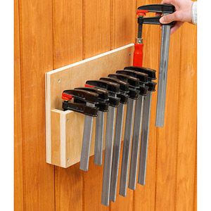 a person holding a set of tools in front of a wooden wall with several holes