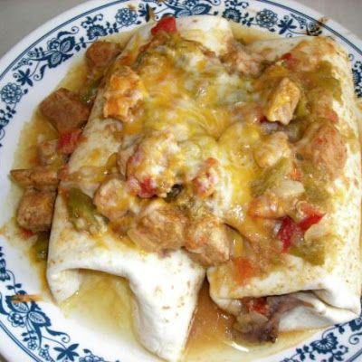 an enchilada covered in meat and cheese on a blue and white plate