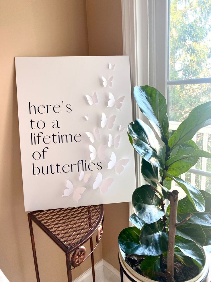 there is a sign that says here's to a life time of butterflies next to a potted plant