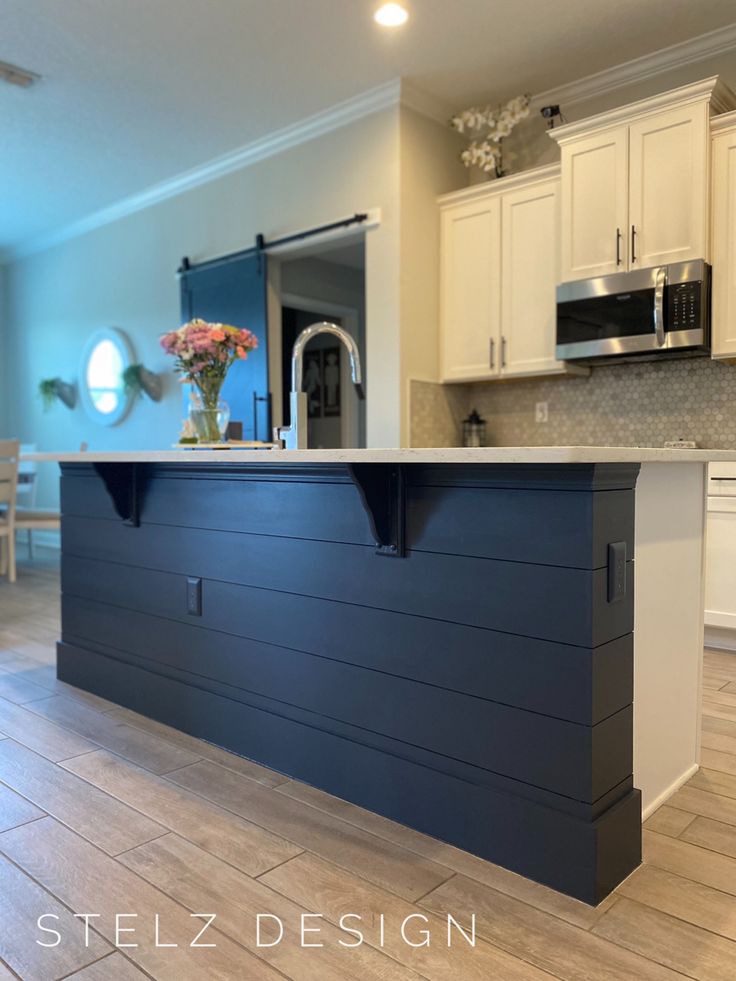 a kitchen with an island in the middle of it and lots of cabinets on both sides