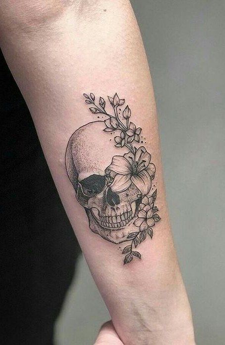 a woman's arm with a skull and flowers tattoo on the left inner forearm