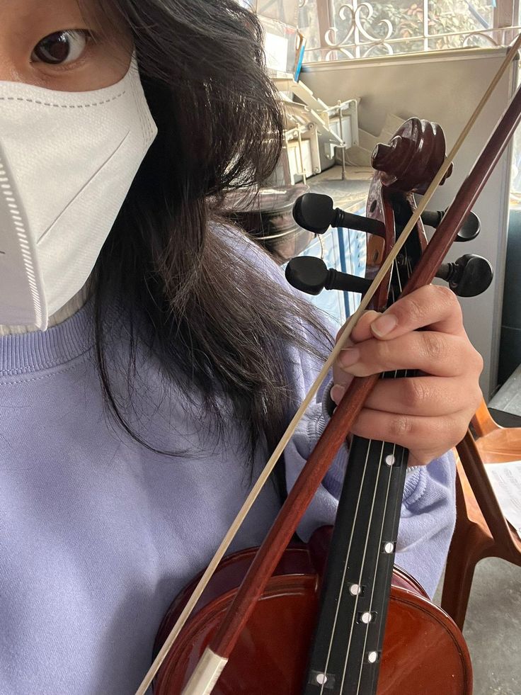 a woman wearing a face mask holding a violin