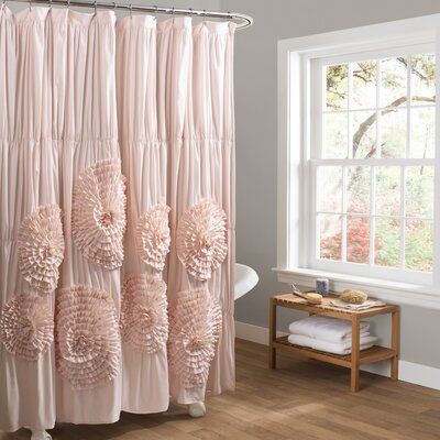 a pink shower curtain with flowers on it in front of a bathtub and window