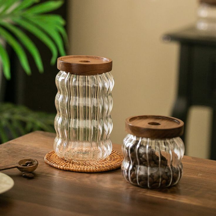 two glass jars sitting on top of a wooden table