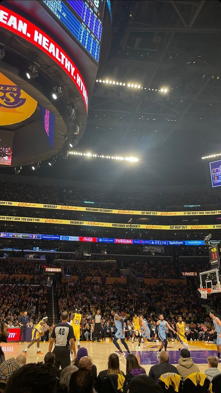 a basketball game is being played in a large arena with people sitting on the sidelines