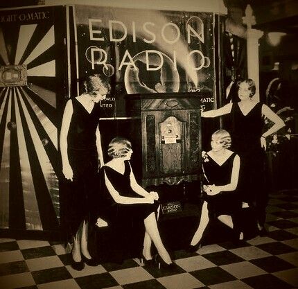 three women in black dresses are standing next to a machine with the words edison radio on it