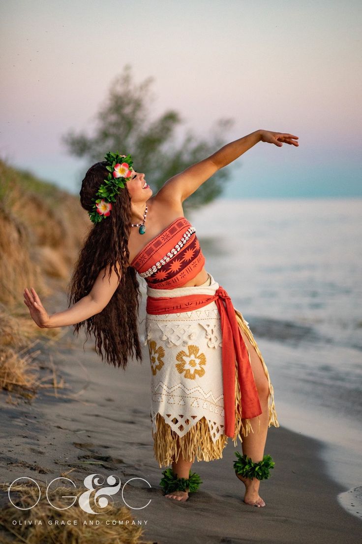 a woman in a hula dancing on the beach with her arms out to the side