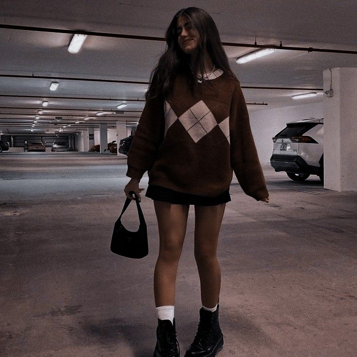 a woman is standing in an empty parking garage holding a handbag and looking at the camera