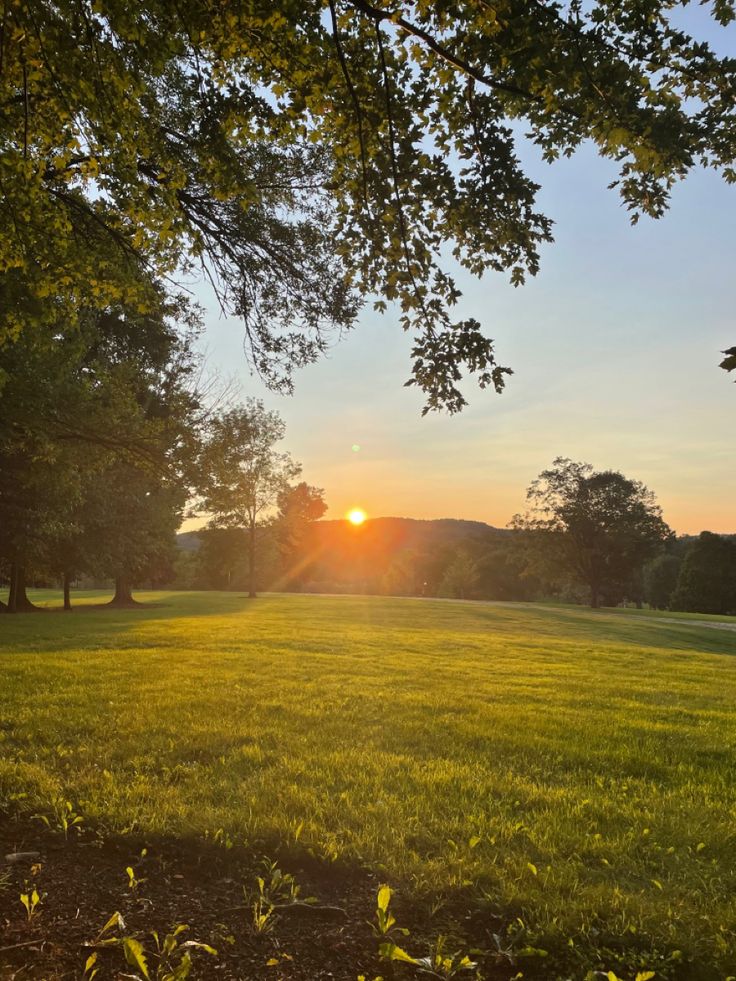 the sun is setting over an open field