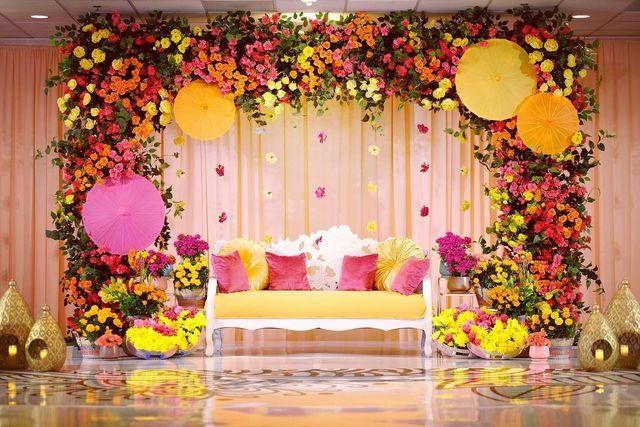 a decorated stage with flowers and umbrellas on the wall for an outdoor wedding ceremony