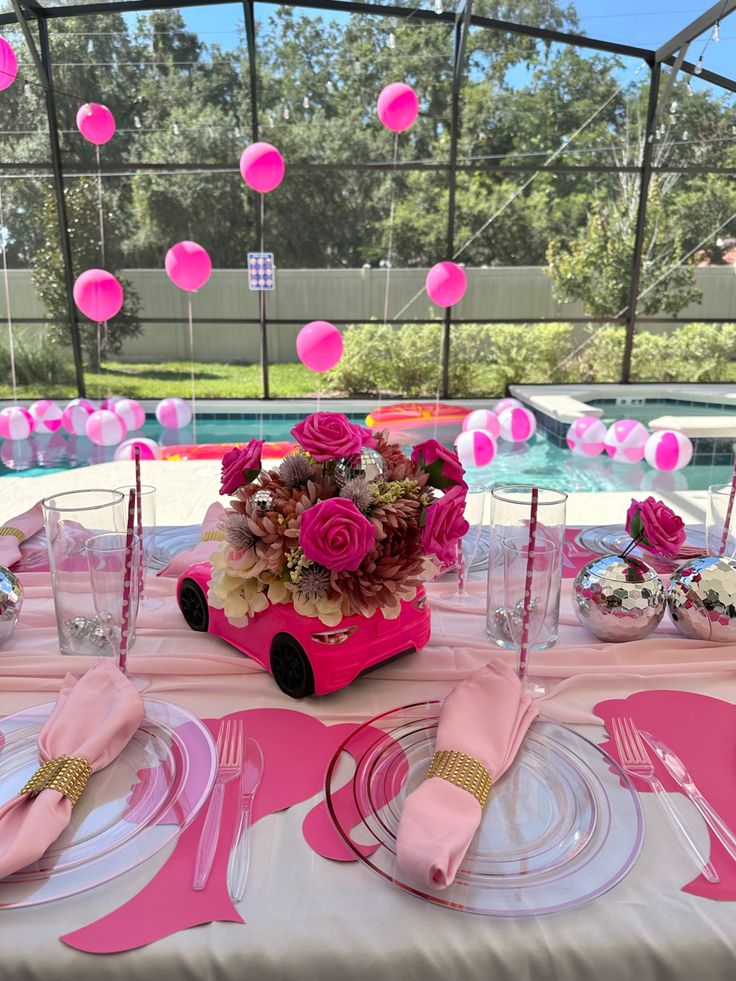 the table is set with pink and white plates, silverware, napkins, and flowers