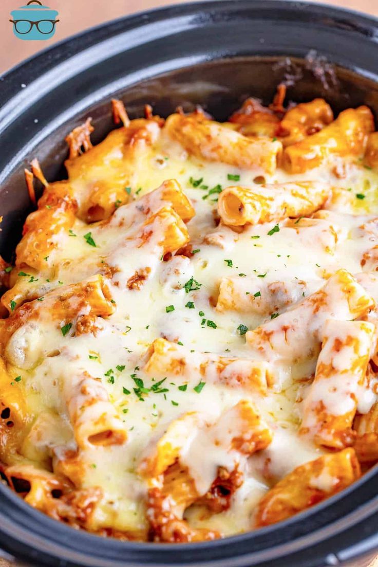 a crock pot filled with cheesy pasta and meat in a white sauce