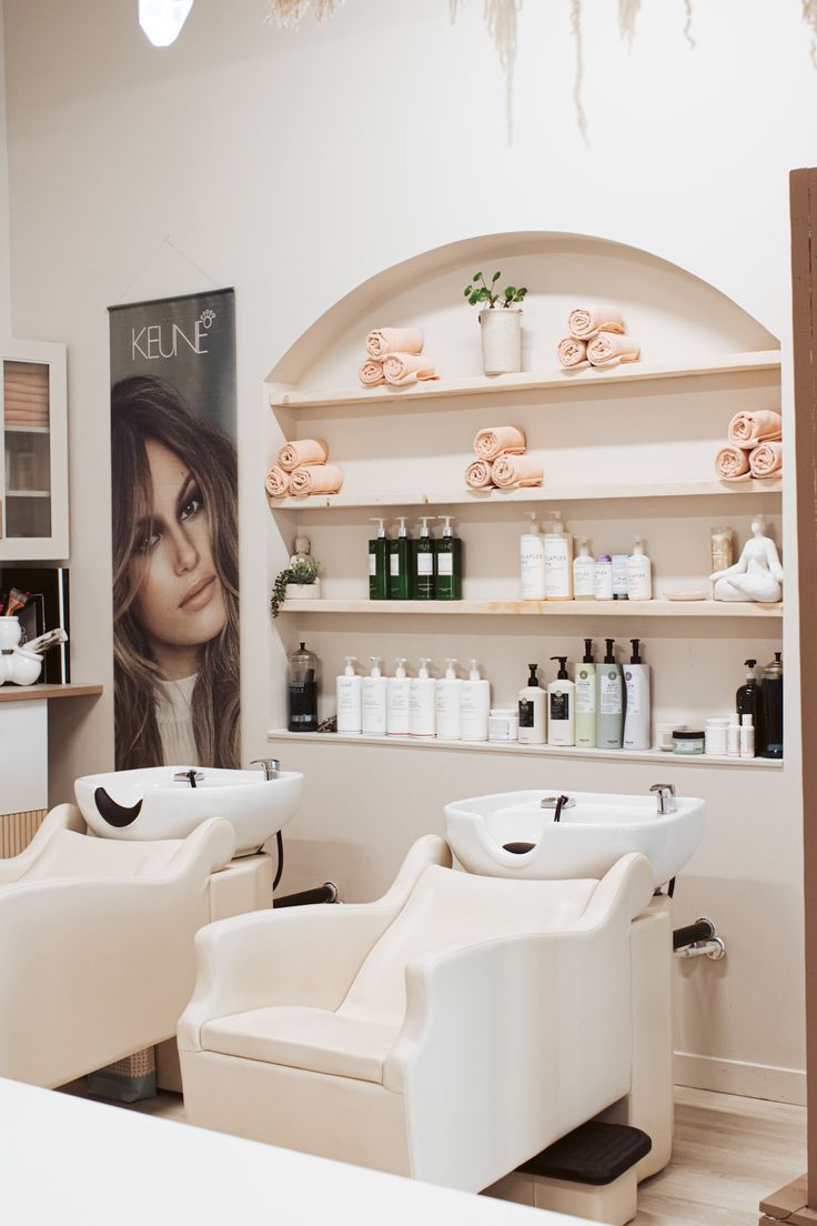 a salon with white chairs and shelves filled with hair products