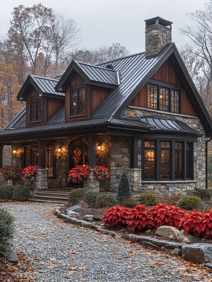 a house with red flowers in the front yard and stone walkway leading up to it