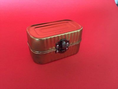 a red and gold suitcase sitting on top of a pink floor