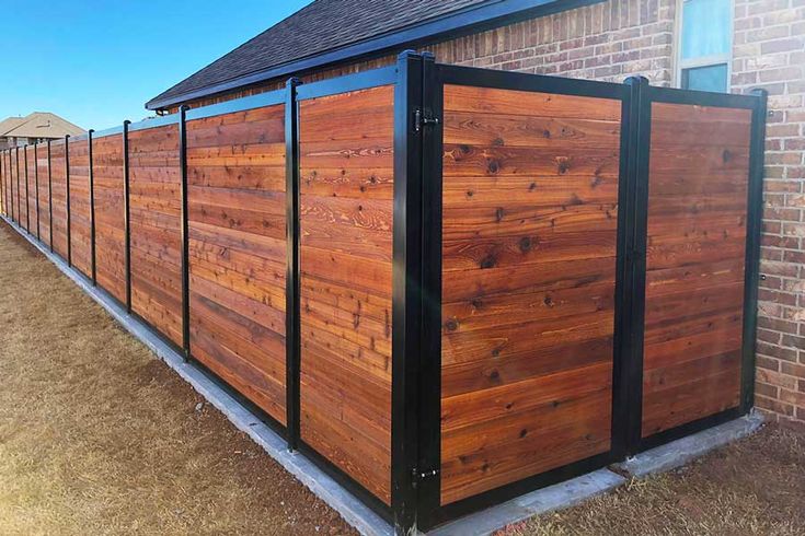 a large wooden fence in front of a brick building with black metal bars on the sides