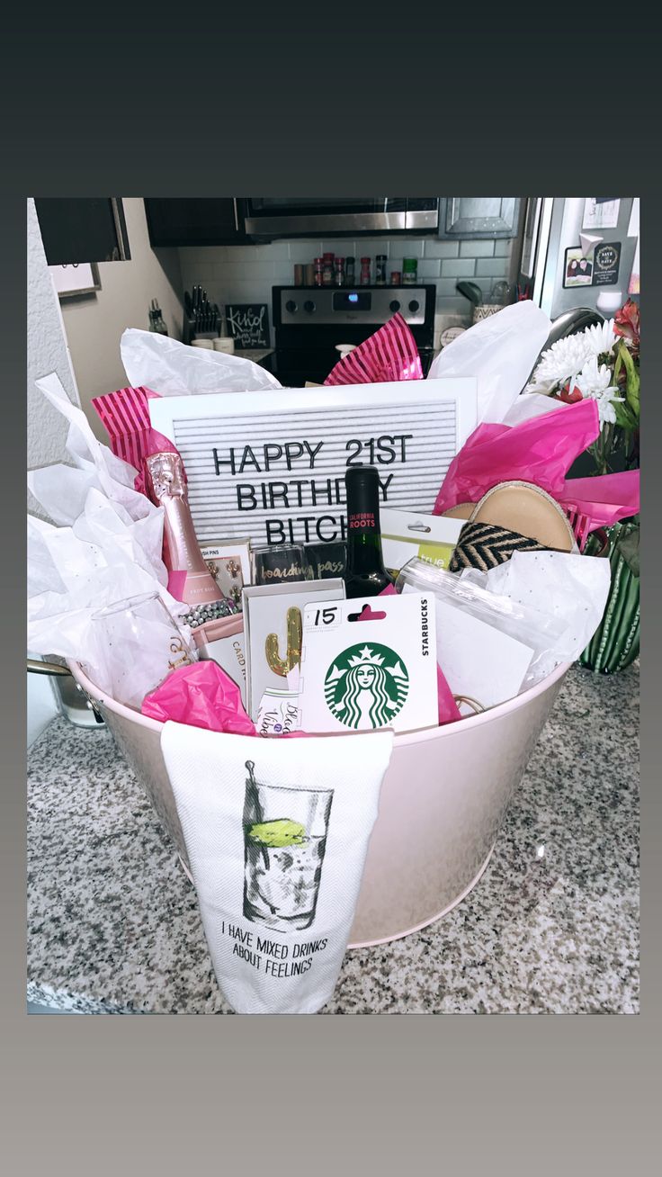 a starbucks gift basket is sitting on a counter top with pink flowers and other items