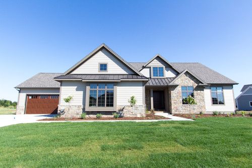 a house with two garages in front of it and grass on the ground next to it